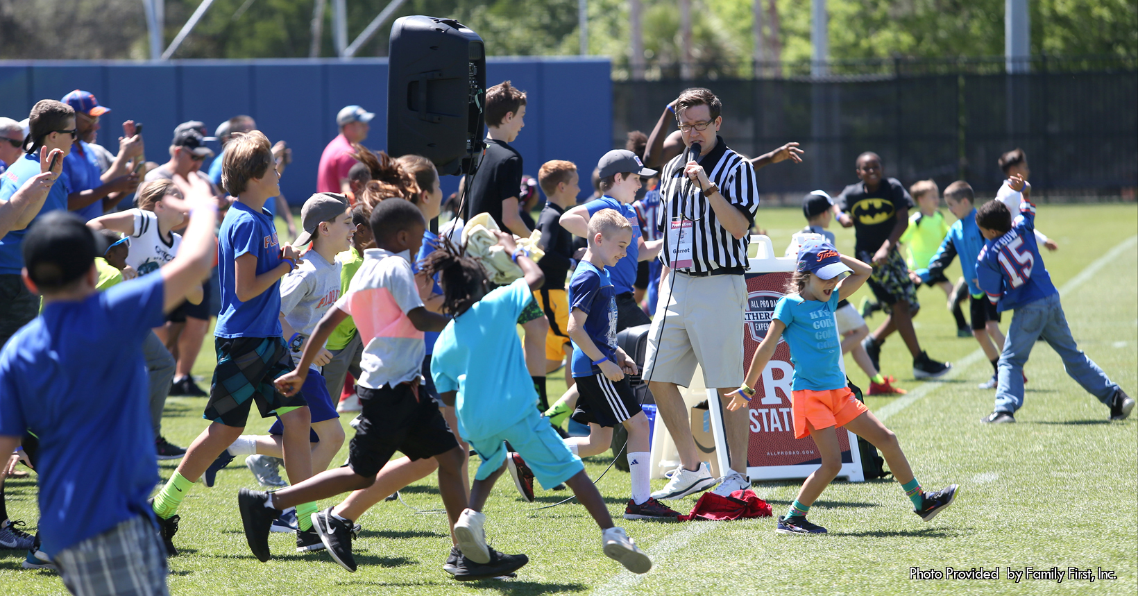 Young children run drills on a football field.