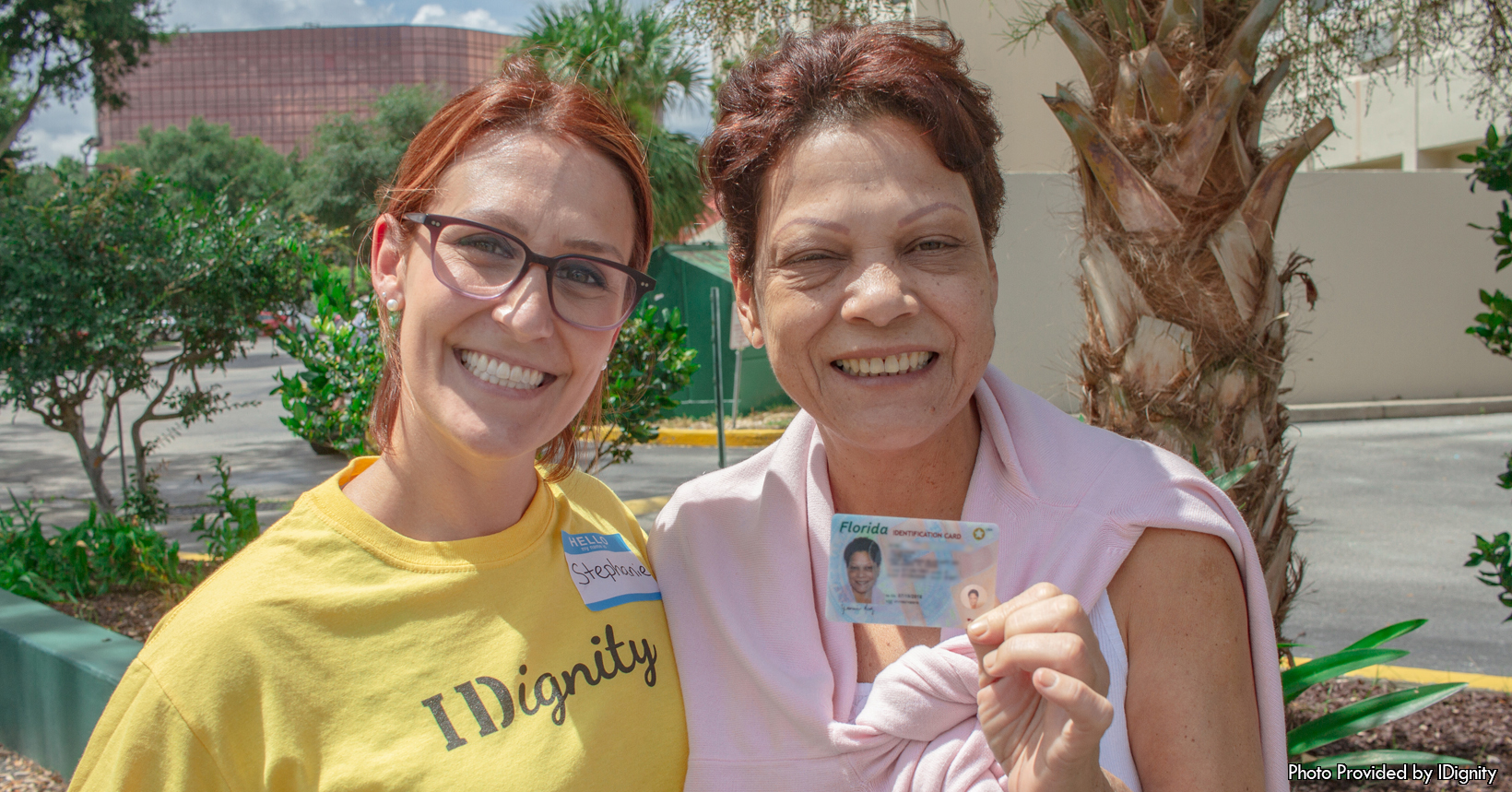 Can you guess why the three people in this photo are smiling from ear to ear? The reason they are all smiling is due to the fact that the young gentleman in the middle of the photo just received his driver’s license. In the Florida area there are a lot of people who don’t have any form of ID. So there are a lot of things in everyday life that these people can’t be a part of. For this young man he couldn't drive a motor vehicle since before the time during this photo he did not have a driver's license. This photo was taken and provided to us by the staff members over at IDignity. This photo was taken during one of their service-fair events that are held once every month. In this point of time the three individuals are standing outside in a parking lot. Behind them is a large white truck and a building that is made out of bricks. In the back right of the photo is an older lady who is volunteering for IDignity during this service-fair event. In addition, in the bottom left hand corner of the photo is an African-American gentleman wearing a black hat. The young man is wearing a salmon colored polo shirt. The shirt has horizontal lines that run across the front and back of the shirt in colors of white and black. To the left and right of the man are two volunteers for IDignity. Both of the IDignity volunteers are wearing light blue shirts with the IDignity logo on the front of the shirts. On the left side is Chelsea and on the right side is Nar. One special thing about Nar is that she speaks Arabic, which allows her to communicate with Arabians who can’t speak English that well.