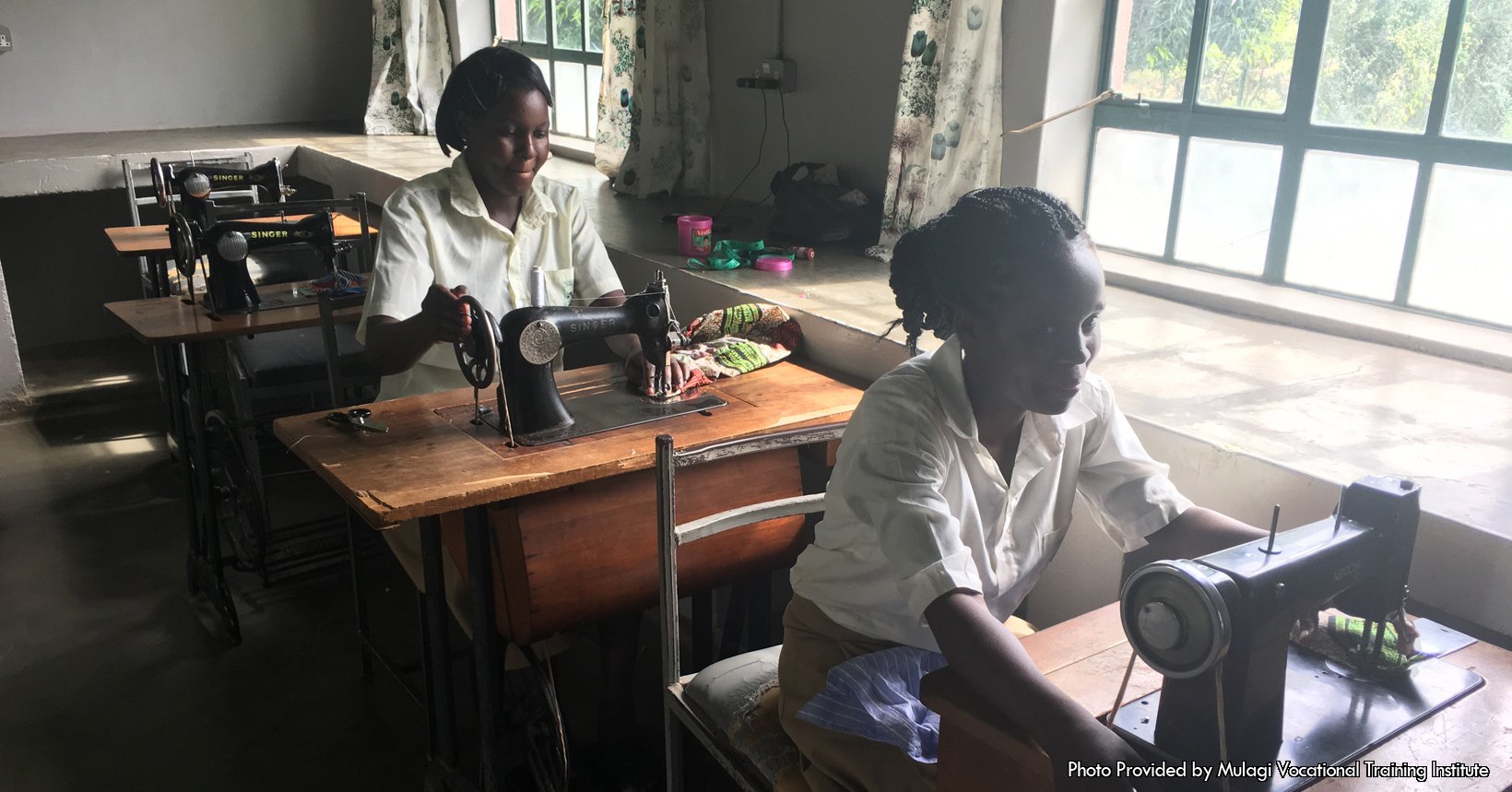 A sewing classroom with two students working diligently