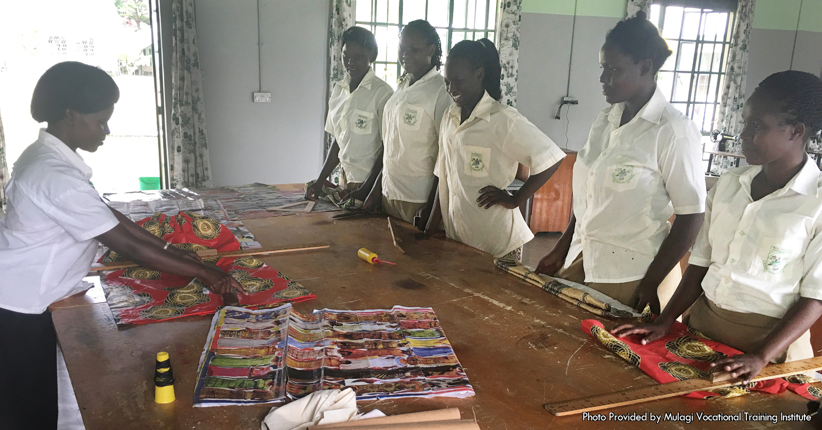 A sewing class where students look at layout while a teacher talks about measurements