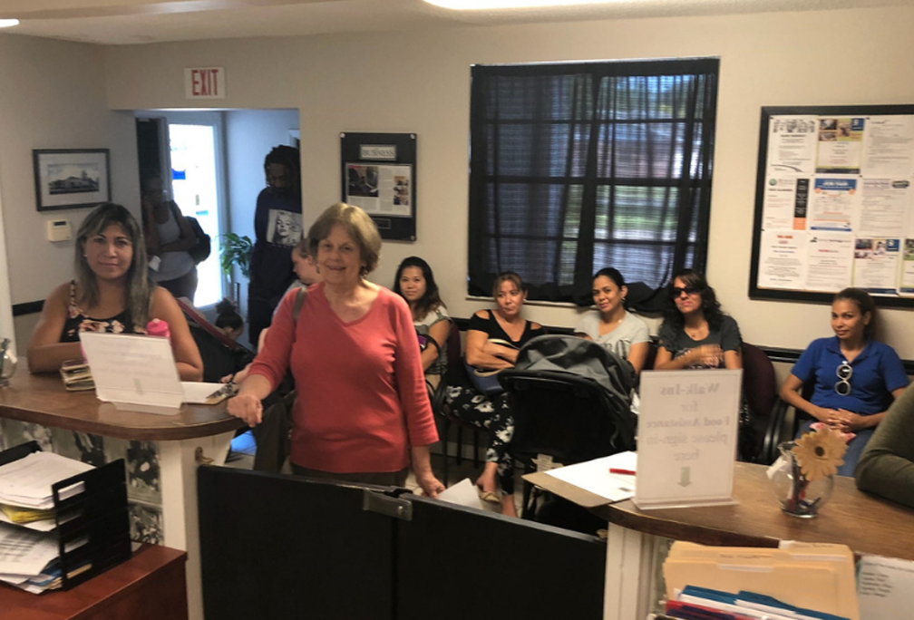 In the Central Florida area there are many who still need a job even though the unemployment rate has reached below 3%. The photo provided by Christian HELP, shows us first-hand just how many people can come to their office on a daily basis. In the center of the photo lies the waiting room of the Christian HELP agency.  At this moment in time the waiting room is filled with potential clients to the point that some people have to wait outside the main office. In the top left corner there are two job seeking clients, one who is an older gentleman and the other is a young woman. Directly in front of them is another client who is standing next to the door for employees only, patiently waiting for her turn. In addition, next to her are two more ladies seeking a job, one in a red long sleeve shirt and the other in a black tank top.  On the far left of the photo stands another client in a green sweater. Directly behind the lady in the red sweater and the two young woman to the left and the right of her, sits six more women eagerly waiting for Christian HELP. On the far left is one woman who is looking at the two individuals standing next to the exit.  Sitting next to her is another woman wearing a white shirt with stripes that run down her shoulder. As for the rest of the women, one of them is wearing a black shirt with openings on the shoulders, another wearing a grey shirt with her baby stroller, and for the last two, one is wearing a black shirt and the other a blue polo shirt.  Although these people are here seeking a job they all come from different parts of life, and Christian HELP is here to help all of them.