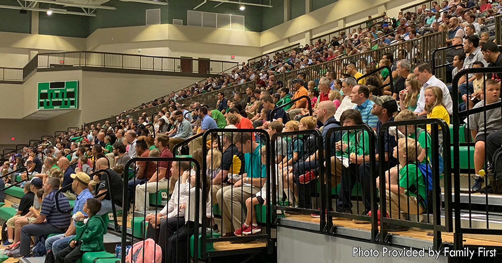 All Pro Dad is having all the fathers and their children sit together on the bleachers. They are looking onto the court waiting on the next step for their time together.