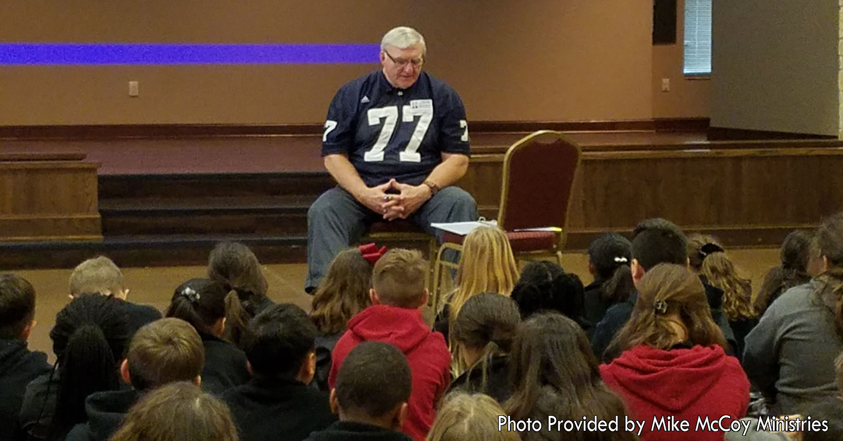 Young children are listening to Mike McCoy as he gives one of his faith-based speeches. The children are listening to Mike talk about overcoming challenges in life. He lets the young kids know through faith, friends, and family there is nothing that they cannot overcome.