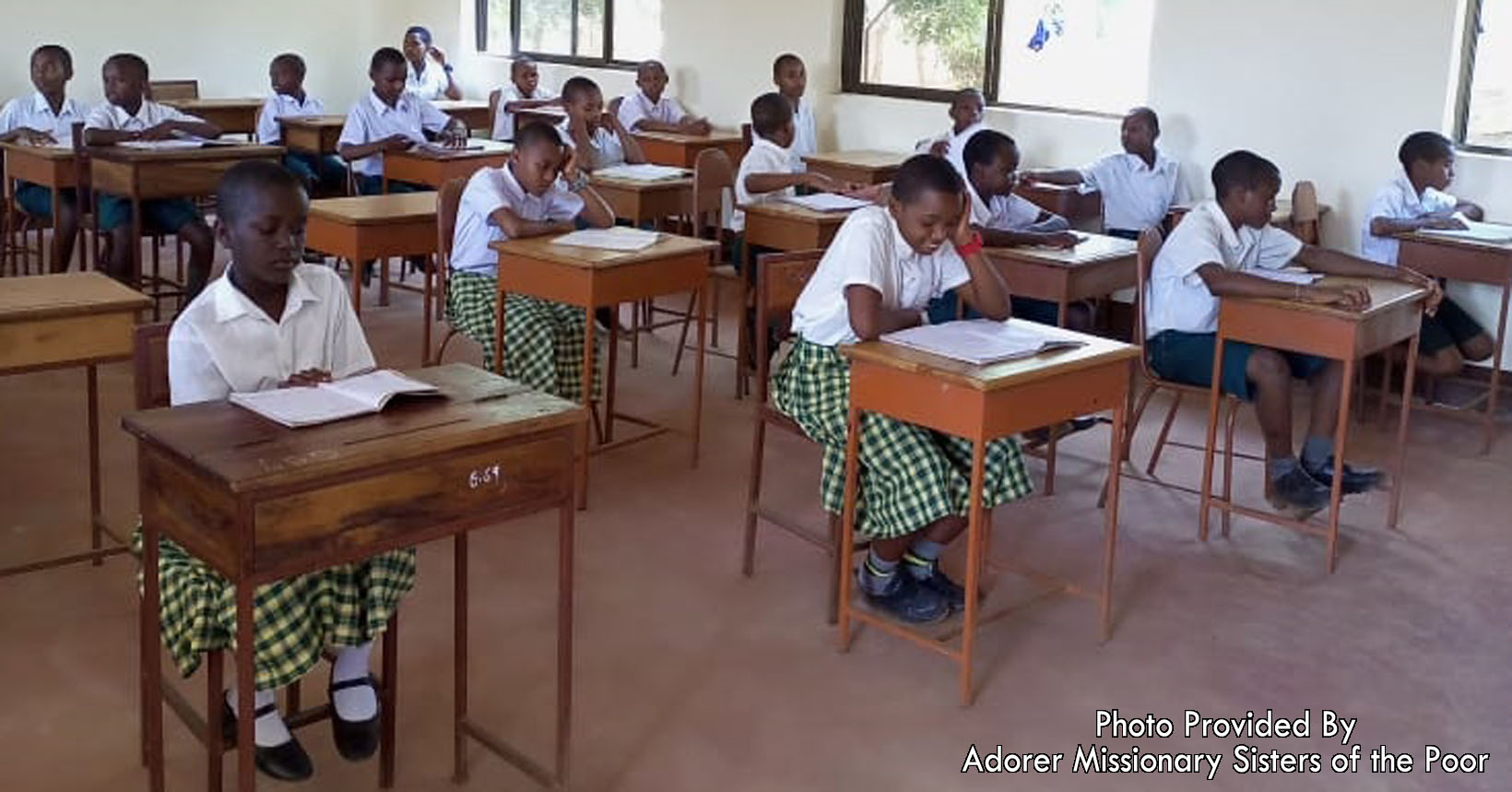 A group of young students at their desks with books ready to learn.