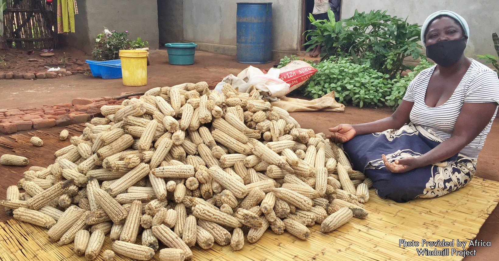 Shelling corn on a mat, Mercy is very happy to be able to produce additional food.