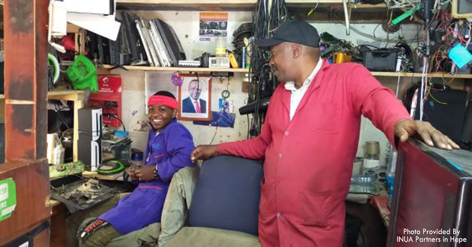 Two men work repairing electronics.