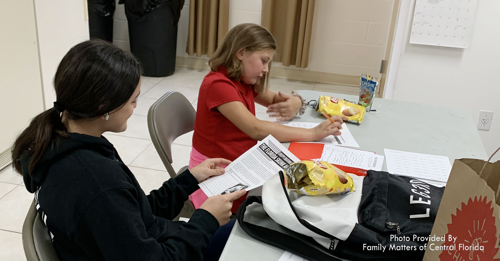 Chloe a member of Family Matters, is working with a student who is reading a book on animals.