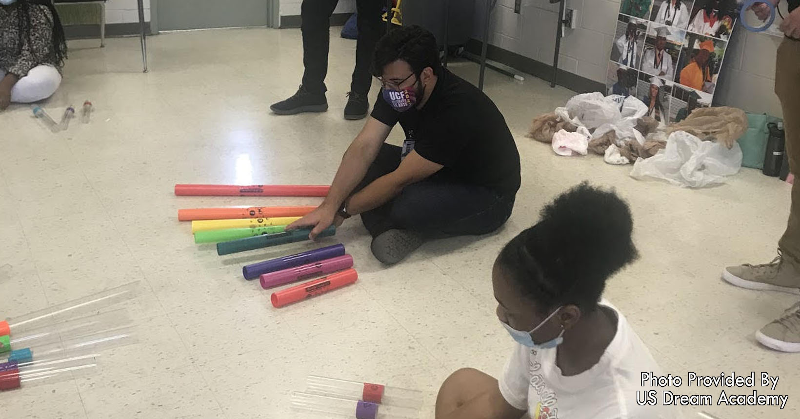 Musical education class where children use plastic pipes as percussion instruments.