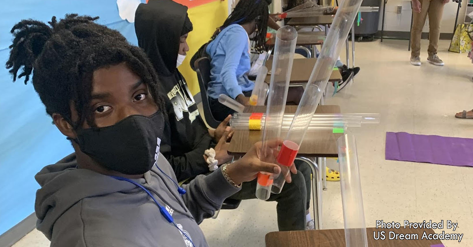 A student shows plastic pipes color coded with musical notes.